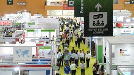 View across a well-attended hall at Laser World of Photonics India with numerous exhibition stands and banners hanging from the ceiling.