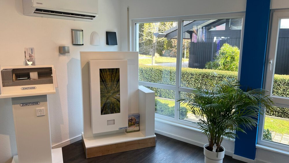 Moderner Raum mit großen Fenstern, Topfpflanze, Klimaanlage und Schränken auf dunklem Holzboden.