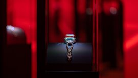 A silver trophy in a glass display case, illuminated against a dark red background.