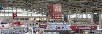 A large exhibition hall with numerous stands and large red 