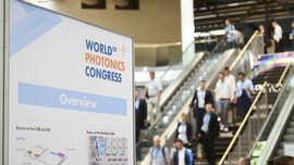 Sign with an overview map of the World of Photonics Congress. An escalator with people can be seen blurred in the background.