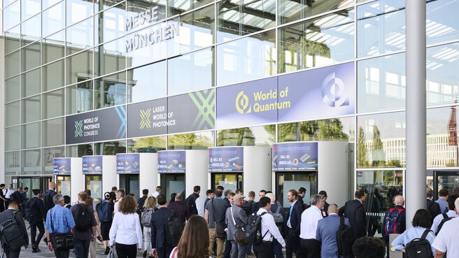 Teilnehmende betreten den Haupteingang der Messe München zur Fachmesse World of Quantum 2025.