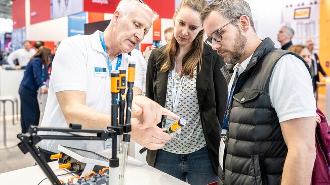 Demonstrating a laboratory instrument to two customers at a trade show stand