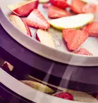 Pieces of strawberry and apple lie on a kind of three-tiered tray device