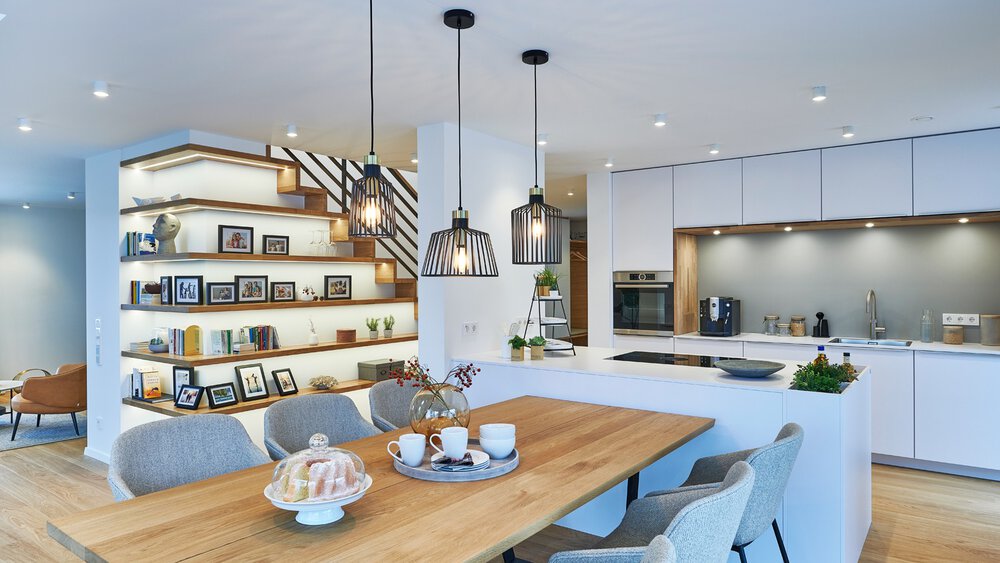 Moderne Küche mit einem hölzernen Esstisch, Hängelampen und offenen Regalen mit Fotos und Dekor.