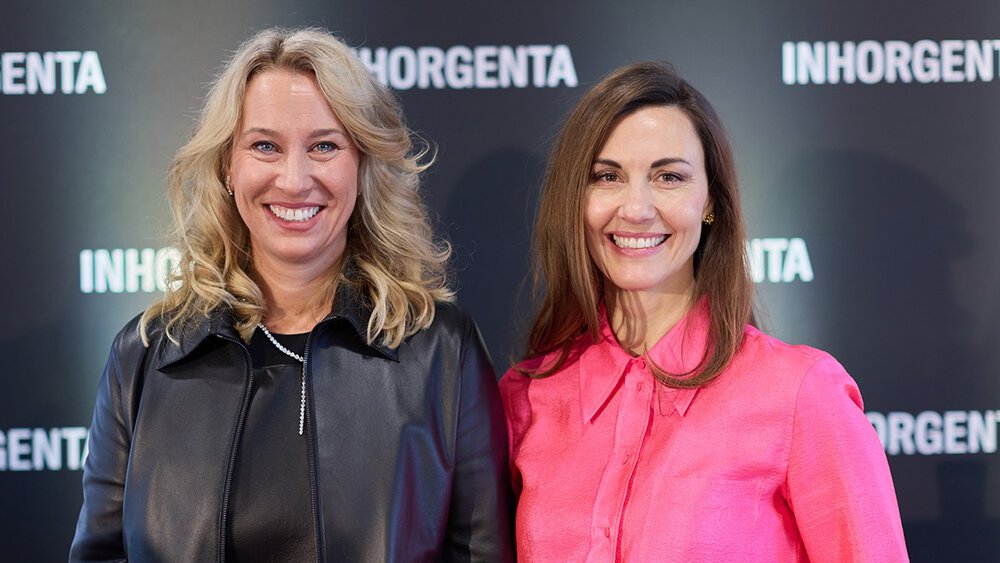 Two women smile in front of a black background labelled INHORGENTA.