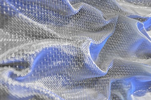 Close-up of a crumpled metallic mesh fabric in shades of blue and silver, featuring a detailed texture and pattern.