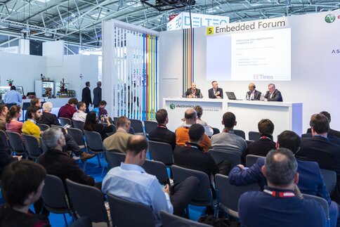 Four participants in a panel discussion on a stage at electronica talk to an audience about new opportunities through 5G.