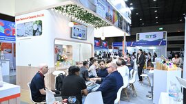 In an exhibition area at ceramitec, numerous visitors sit in groups at tables and chat with each other.