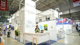 A stand for the “German Pavilion” at a ceramitec event abroad, with large display walls and a woman standing at a counter.