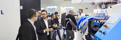 Several visitors stand at a machine at productronica and talk about the exhibit.