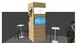 Messestand mit Holzpaneel, Paravent, Hockern, Tischen und einer vertikalen Pflanzenfigur. Mann steht in der Nähe.