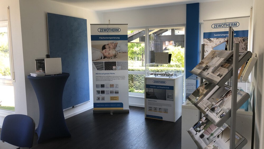 Showroom mit Ausstellungsständern, Prospektständer, Stehtisch mit schwarzer Husse und großen Fenstern.