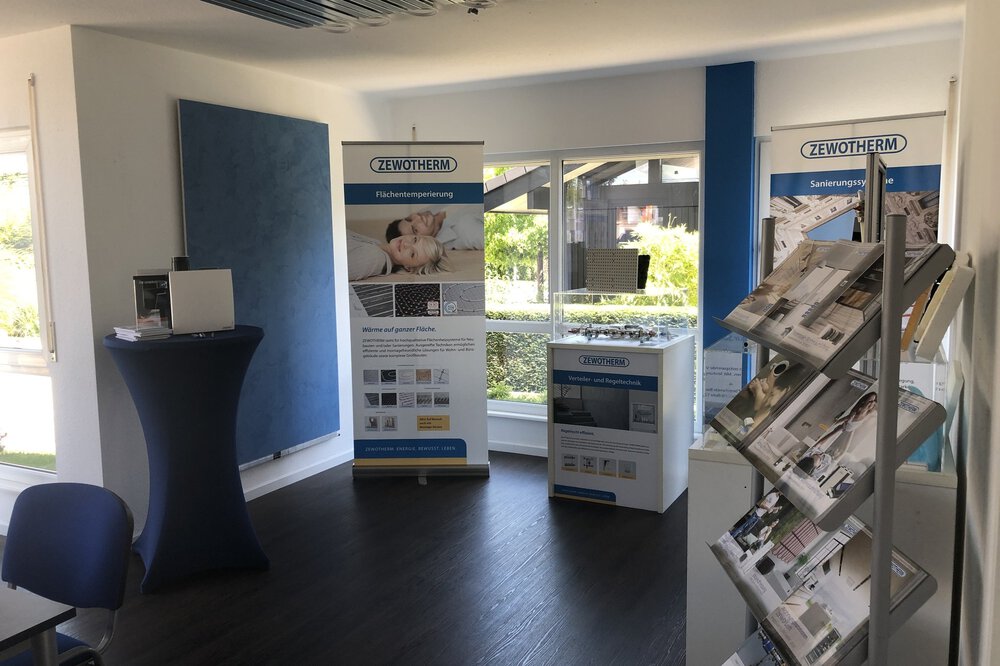 Showroom mit Ausstellungsständern, Prospektständer, Stehtisch mit schwarzer Husse und großen Fenstern.