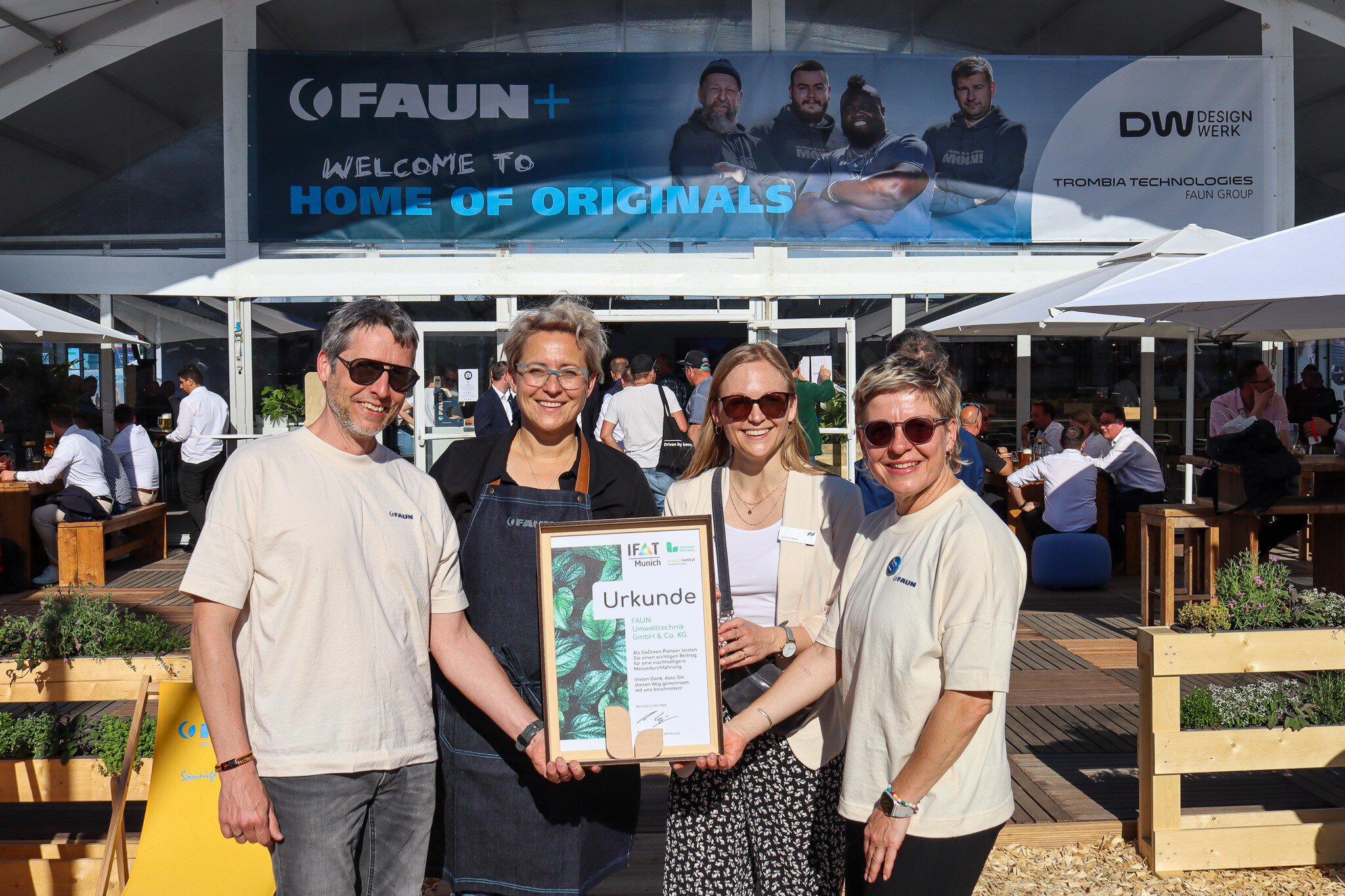 Presentation of the GoGreen Pioneer and GoGreen Exhibitor certificates by the IFAT Munich team, with three employees and the managing director receiving the awards.