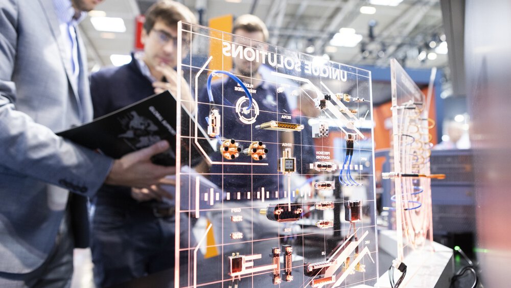 Two people examining a transparent board with technical circuit diagrams and electronic components indoors