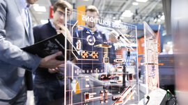 Two people examining a transparent board with technical circuit diagrams and electronic components indoors