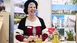 Exhibitor in traditional attire cheerfully presents Upper Bavaria's travel highlights.