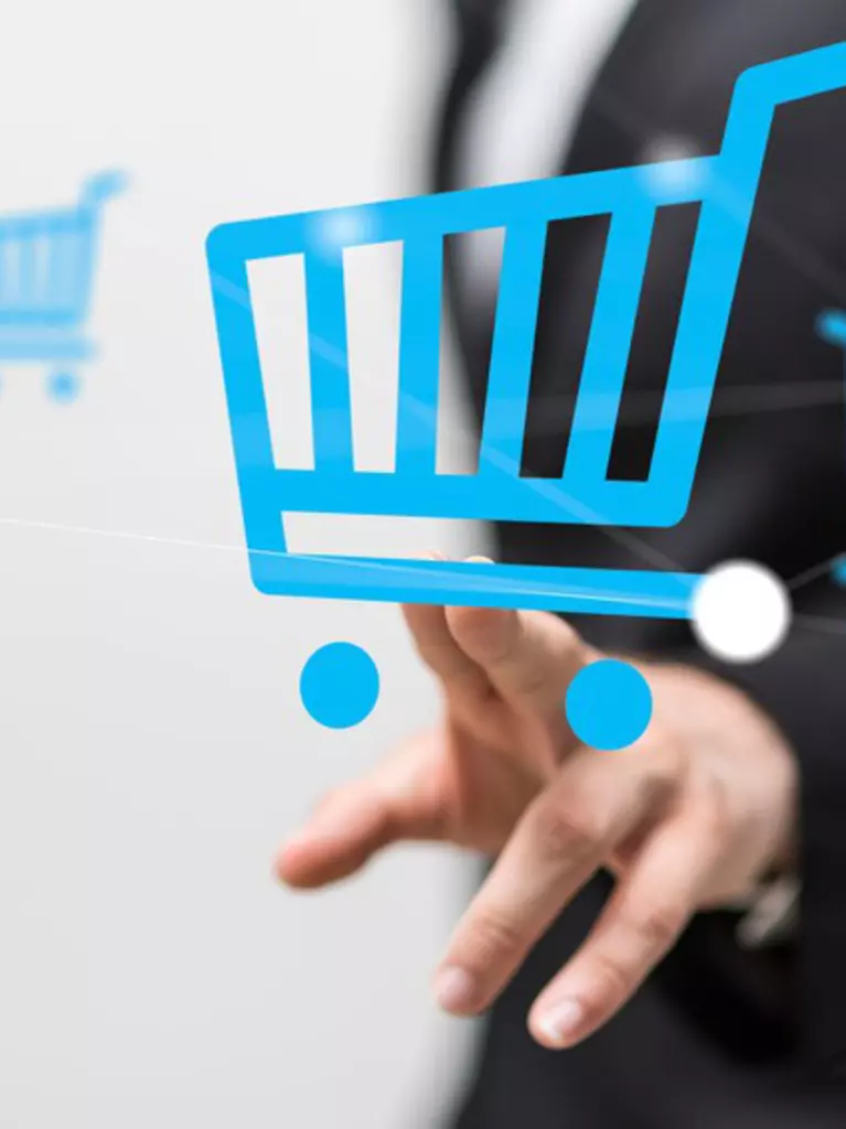 Die Hand einer Person drückt von hinten gegen die Grafik eines blauen Einkaufwagens. Weitere Einkaufswagensymbole schweben in der Luft.