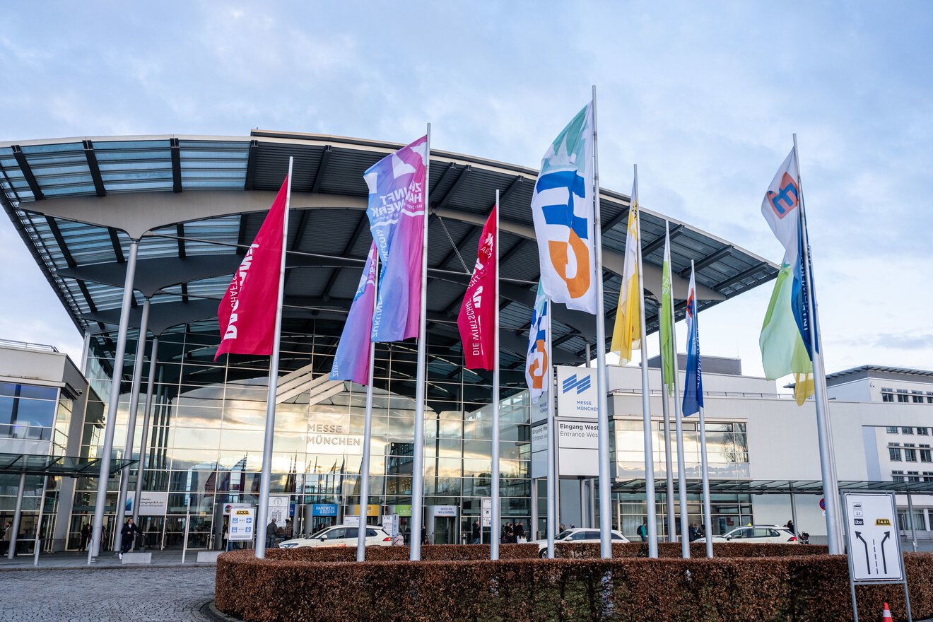 Auf dem Foto sieht man bunte Flaggen vor einem großen gläsernen Gebäude