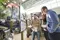 Close-up, a man stands in an exhibition hall next to a camping street sign and shows something in a catalog