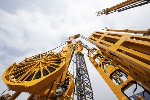 Large yellow drilling rig rises into the cloudy sky.