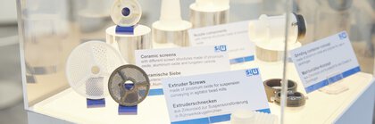 Product display with ceramic sieves and extruder screws, identified by labels and metal components on a white background.
