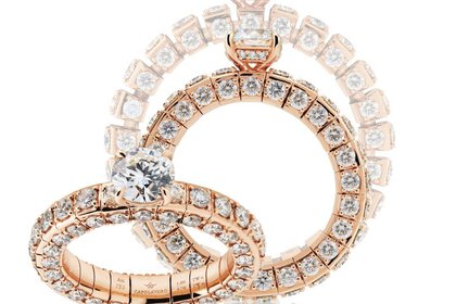 Three wide, multi-section rings set with numerous round diamonds and each featuring a large gemstone set on the side.