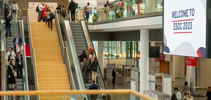 Menschen in einem belebten Konferenzzentrum mit einem großen Bildschirm, auf dem 