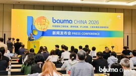 A press conference for bauma CHINA 2026, with participants seated and a speaker standing on the podium in front of a large yellow-and-blue event backdrop.