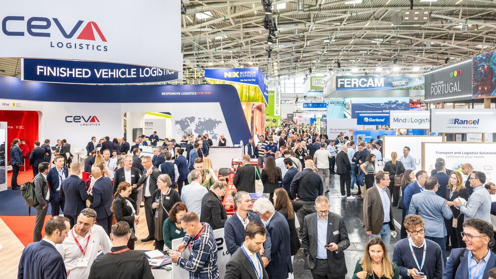 Zahlreiche Messebesucher stehen und gehen zwischen diversen farbenfrohen Messeständen der transport logistic Americas.