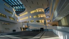 Spacious, modern building interior with curved walls, large windows and effective lighting.