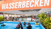 Blick auf ein großes Wasserbecken in einer Messehalle.