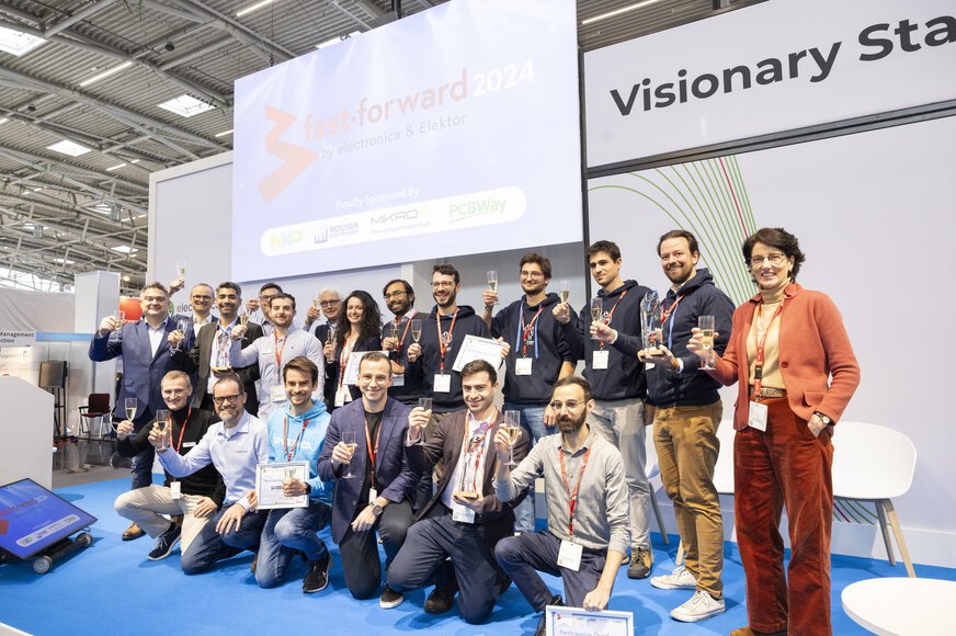 Eine Gruppe Menschen mit erhobenen Sektgläsern posieren auf der Bühne der electronica Visionary Stage.