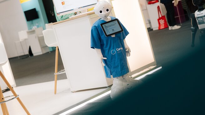 Service robot in blue clothing at an exhibition booth during DMEA