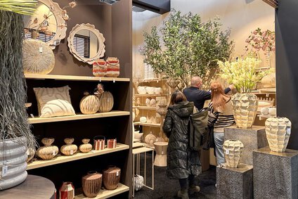 auf dem Foto sind Leute in einem Stand der TrendSet zu sehen, die ein Verkaufsgespräch führen. Es sind vor allem Vasen und Spiegel zum Verkauf.