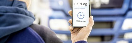 View over the shoulder of a man holding up a smartphone. It shows the time slot for loading a lorry at the Munich trade fair grounds.