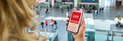 Eine Frau hält ein Smartphone in der Hand, auf dem man den transport logistic Podcast sieht.