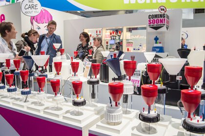 Rote Safety Waste Caps an Ausstellerstand auf der analytica mit Personen im Hintergrund