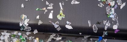 Nahaufnahme verschiedener bunter Plastikfragmente, die von einem Fließband rieseln.