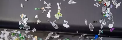 Nahaufnahme verschiedener bunter Plastikfragmente, die von einem Fließband rieseln.