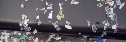 Close-up of various colorful plastic fragments trickling off a conveyor belt.