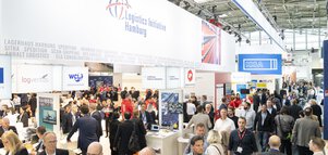 A bird's eye view of the well-attended transport logistic trade fair stands, focussing on a banner with the 
