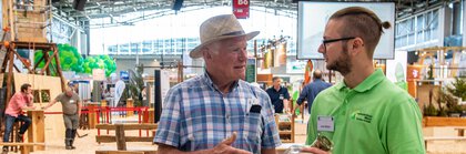 A visitor is talking to an exhibitor at a trade fair stand of INTERFORST