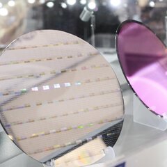 Two silicon wafers on display, one reflective, one shimmering violet, as the basis for integrated photonic chips.
