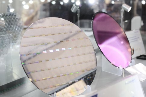 Two silicon wafers on display, one reflective, one shimmering violet, as the basis for integrated photonic chips.