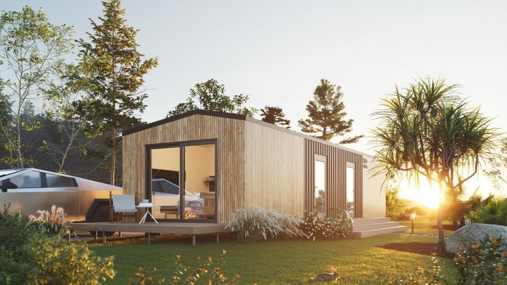 Moderne Holzhütte mit großen Fenstern, umgeben von Bäumen und Gras, bei Sonnenuntergang. Auf dem Rasen sitzt ein kleiner Hase.