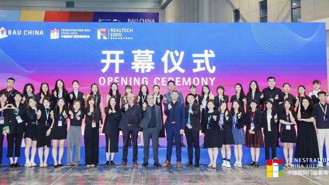 Eine große Gruppe von Menschen in Businesskleidung steht vor einem blau-violetten Banner mit der Aufschrift 