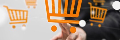 Eine Hand tippt auf ein orangefarbenes Einkaufswagensymbol auf einem transparenten Bildschirm.