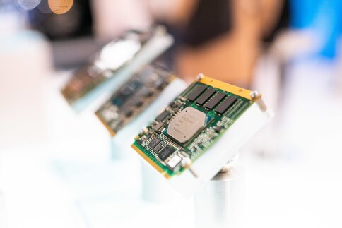 Close-up of a computer board with various electronic components, displayed at a trade fair stand.